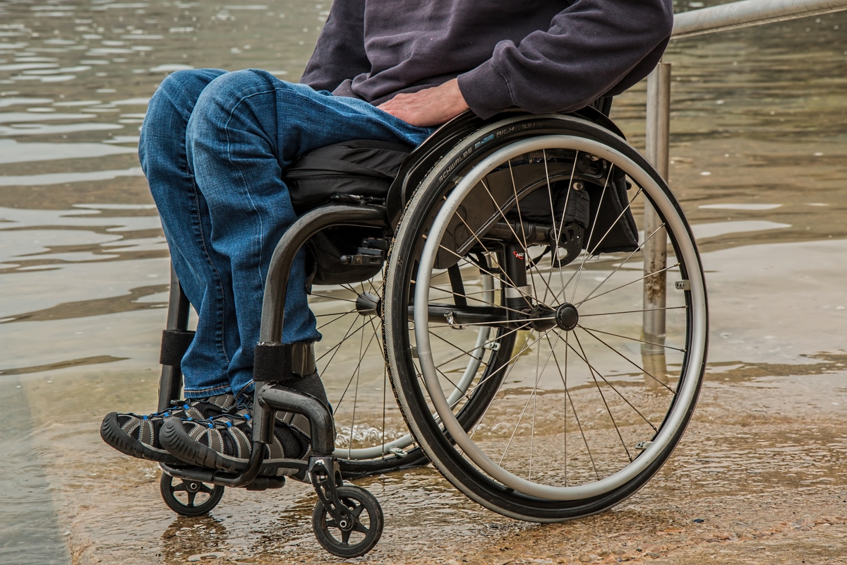 Wheel chair user sitting at the side of pond in the park representing the work Albion Mobility carry out.